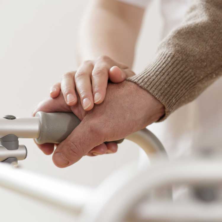 Hände von Rollstuhlfahrer und Physiotherapeut